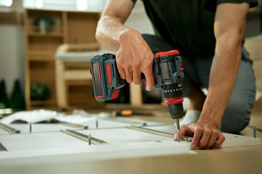 Closeup man is working with furniture assembly using electric screwdriver