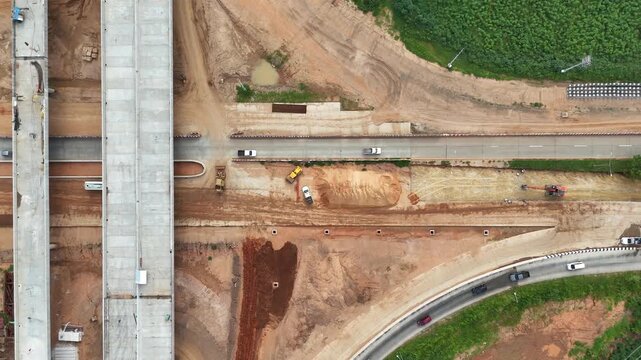 Aerial drone footage of bridge construction across a road intersection in rural, showing civil engineering work, infrastructure development, and transportation project in progress