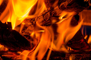 Close-up eines brennenden Haufens Holz, mit gl&uuml;henden Holzscheiten und orange z&uuml;ngelnden, hei&szlig;en Flammen in einem Brennofen