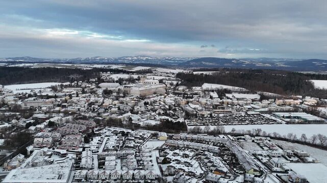Luftaufnahme von St. Florian bei Linz mit schneebedeckten Feldern und Wohngebieten. Luftaufnahme von St. Florian bei Linz mit schneebedeckten Feldern und Wohngebieten. Dunkle Wolkenfelder kontrastiere