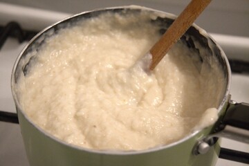 Close-up of horseradish cream in cooking pan during homemade ham roll preparation. Traditional home cooking process, festive appetizer preparation, seasonal food concepts, family meal and culinary