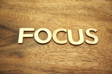 Focus word composed of wooden letters on wood material background. Concentration, productivity,...