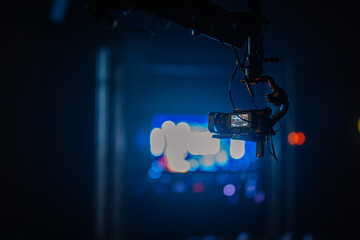 Camera suspended from a crane captures vibrant stage lights in a dark venue, showcasing the excitement of a live performance with dynamic visual elements