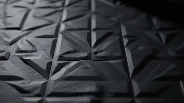 Abstract dark grey geometric background featuring a dynamic three-dimensional texture with angular triangles and raised patterns, perfect for modern design and architectural concepts