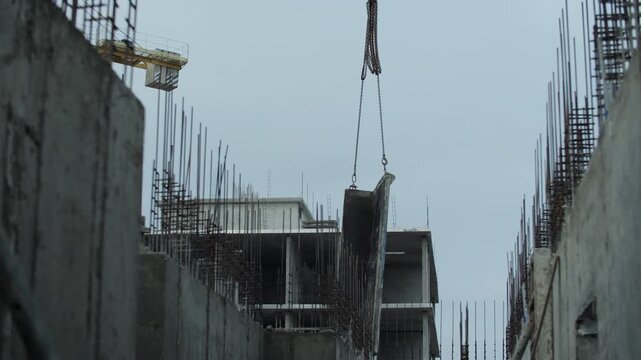 Tower crane lifting concrete formwork between reinforced walls