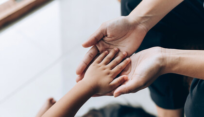 Tender moment as an adult's warm hands gently embrace a child's small hand, symbolizing protection, care, and the profound, unbreakable bond of family love and support