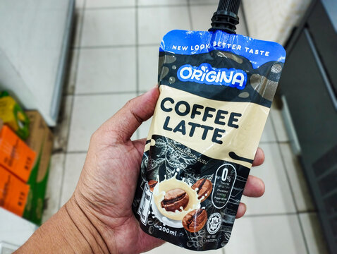 A hand holding a 200ml pouch of Origina Coffee Latte, a ready-to-drink caffeine beverage with a convenient spout.