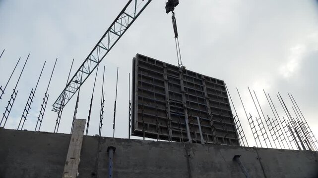 Tower crane lifting large concrete formwork panel