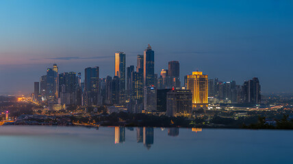 Fototapeta premium Stunning Jakarta Skyline at Twilight: Modern Cityscape with Skyscrapers, Urban Illumination, and Water Reflection in Indonesia at Dusk