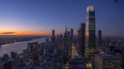 Obraz premium Dramatic Skyline of a Modern City at Dusk with River and Glowing Sunset, Featuring Tall Skyscrapers and Urban Landscape at Twilight