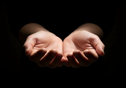 Open human hands gently cupped in darkness, symbolizing offering, care, compassion, hope, trust, giving, support, prayer, humility, and emotional connection on dramatic black background