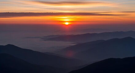 Obraz premium Majestic mountain peaks emerge from a soft sea of clouds as the vibrant sun rises painting the sky with fiery orange and golden hues