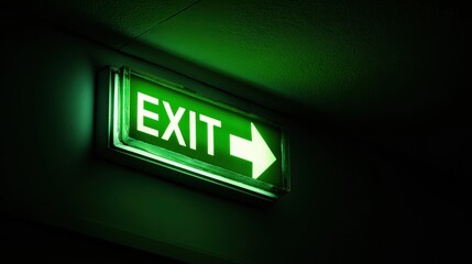 Exit way arrow direction guidance sign green color light emergency exit sign in a dark room.