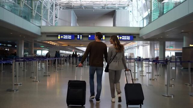 A couple walking with luggage through an airport, embarking on a travel adventure. The airport environment exudes a sense of journey and exploration Stock Video