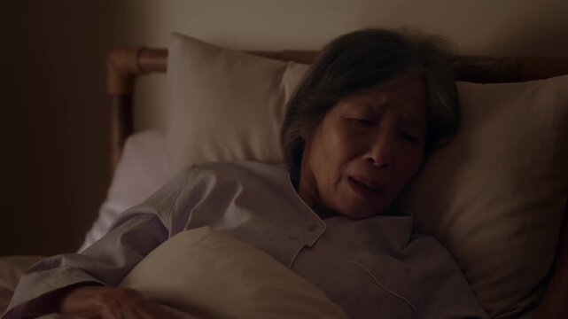 An elderly person lying in bed, showing signs of sadness and discomfort Stock Video