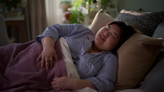 A relaxed individual lying on a bed, expressing contentment and comfort, ideal for promoting relaxation and wellness. The environment is inviting and warm, which conveys peacefulness  Stock Video