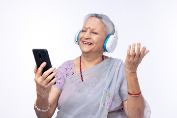 Senior woman listening music using digital tablet and headphones at home