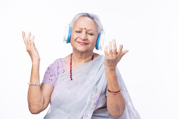 Senior woman listening music using digital tablet and headphones at home