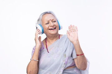 Senior woman listening music using digital tablet and headphones at home
