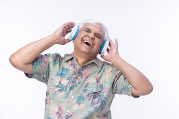 Senior man listening music over headphones and looking up against white background