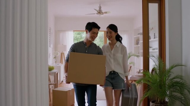 Couple moving into their new home. They are holding boxes and suitcases, symbolizing a new chapter in their lives Stock Video