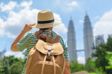 Female tourist in hat with backpack enjoying cityscape, Malaysia