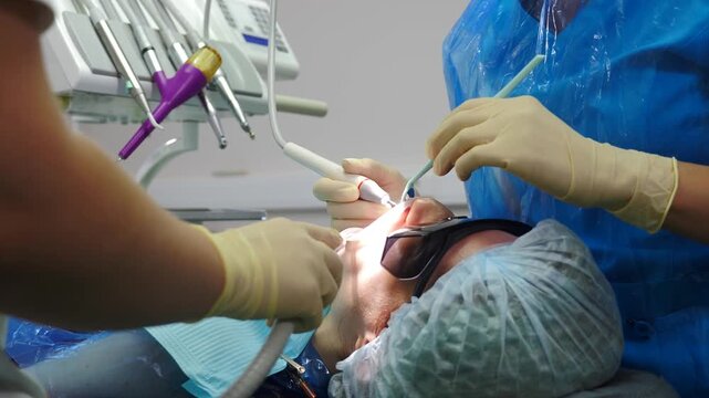 Oral hygiene. Ultrasonic teeth cleaning machine removing calculus and plaque. human teeth treatment. Professional dentist treating patient in modern dental clinic. dental care and hygiene