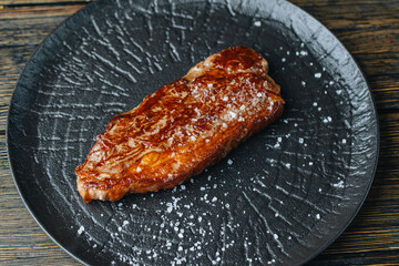 Cooked Beef steak on a dark plate with rustic background