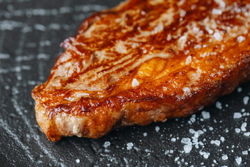 Cooked Beef steak on a dark plate with rustic background