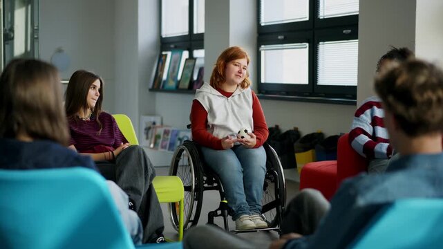Classmates relaxing and talking in high school lounge. Girl in wheelchair among them.