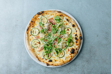 Fresh artisan pizza on a bright background with fresh rucola and ham
