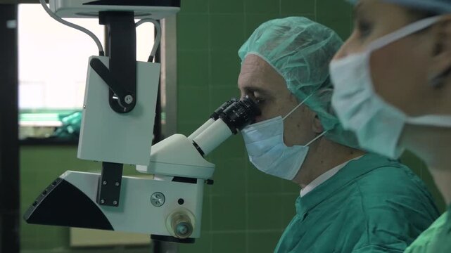 Portrait of surgeon using a specialized surgical microscope for precision eye surgery.