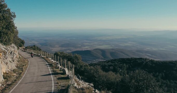 Motorcyclist riding down the access road to the summit of Mare de Deu del Mon in Girona, Catalonia, Spain
