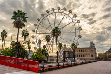 Great Ferris wheel in the port of Barcelona at sunset with golden sky, Catalonia.