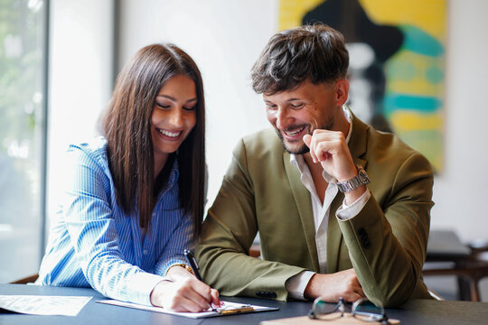 Couple working together in a bright office setting during the day while sharing ideas and taking notes