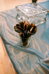 Neatly arranged cutlery spoons in a glass on blue fabric