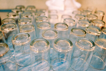 Row of clean inverted drinking glasses on a textured surface