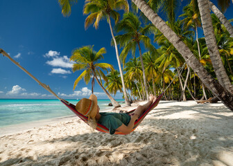 woman relaxing on a cozy and colorful hammock on tropical beach