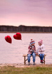 Little boy and little girl on a bench by the lake on Valentine's Day