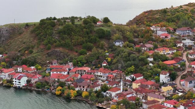 Aerial video of Lin village in Albania, showing hillside homes, dense greenery, and Lake Ohrid in soft autumn light.