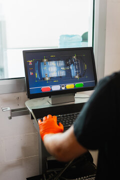 Tire technician checking wheel alignment parameters on a professional technical monitor.