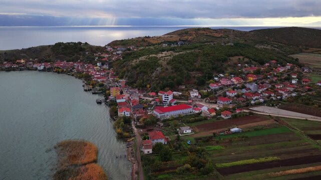 Aerial video of Lin village in Albania, showing hillside homes, dense greenery, and Lake Ohrid in soft autumn light.