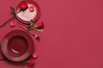 Beautiful table setting for Valentine's Day with candles and rose flowers on red background
