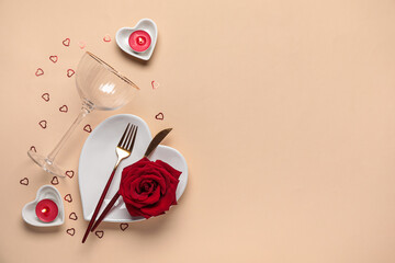 Beautiful table setting for Valentine's Day with candles, confetti and red rose flower on beige...