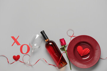 Beautiful table setting for Valentine's Day with paper letters XO, bottle of wine and rose flower on white background