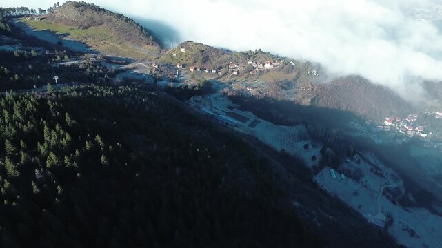 Aerial view of dense clouds covering valleys with snowy mountain ridges rising above the fog, creating a dramatic winter landscape near Sarajevo with clear sky and natural contrast