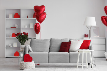 Interior of light living room decorated for Valentine's Day with sofa, lamp and balloons