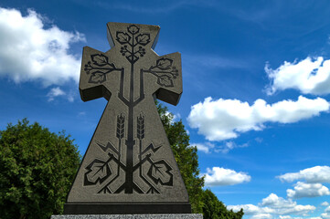Stone cross with carved ornament against blue sky
