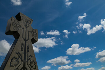 Stone cross with carved ornament against blue sky