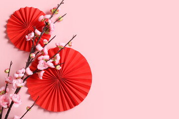Chinese red fans with plum tree branch on pink background with space for text